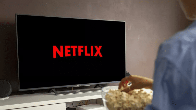Persona con in mano popcorn e guarda Netflix (Foto: Riproduzione - DCI)